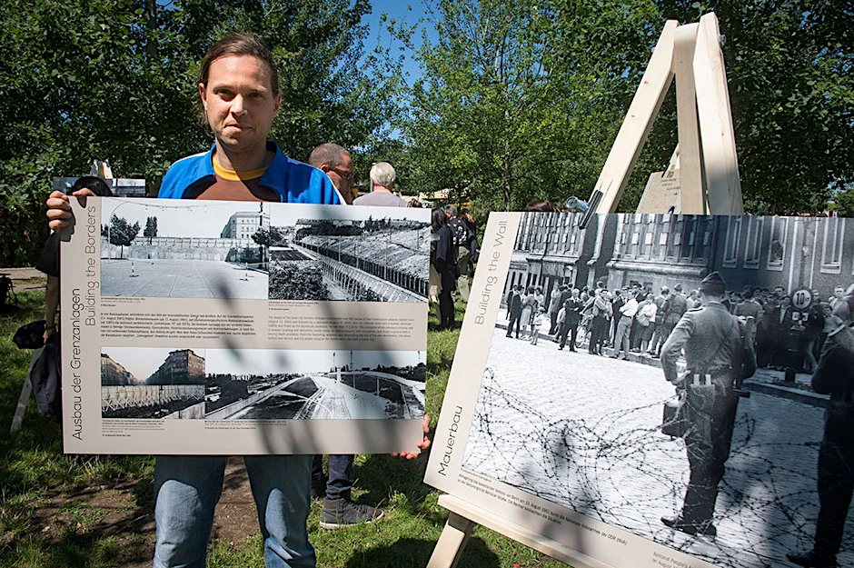Historiker Stephan Müller zeigt eine der insgesamt 15 Tafeln, die jeden Sonntag im Mauerpark zu sehen sind.