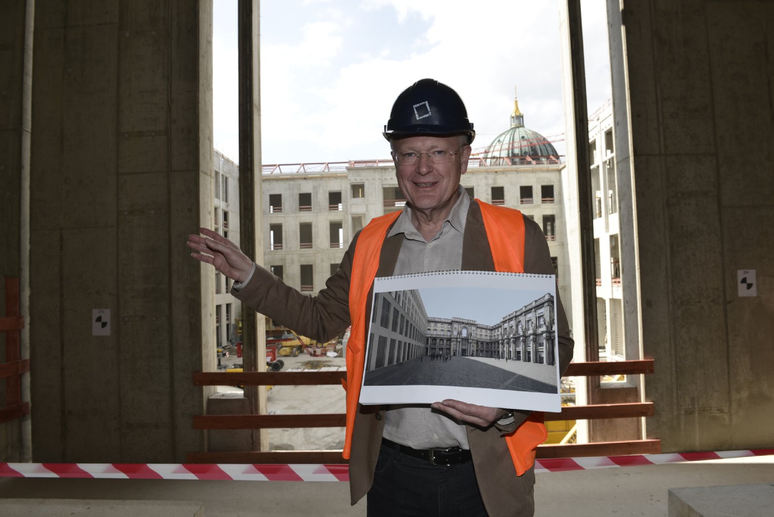 Manfred Rettig vor dem „Schlüterhof“: Er zeigt ein Bild, wie das Gebäude mit Barockfassade aussehen wird.