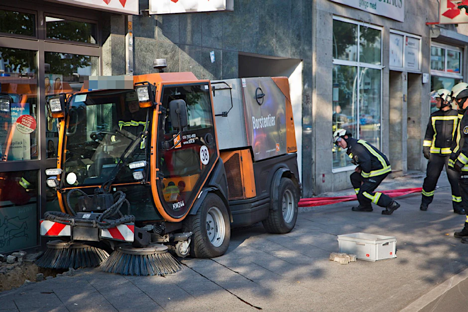 Berlin-Friedrichshain, 4. August 2015: Am frühen Morgen sackt unter diesem BSR-"Borstentier" der Gehweg in der Frankfurter Allee weg. Rumms: Die Kehrmaschine landet in einer Apotheke.