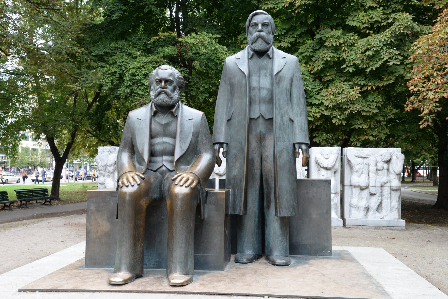 Friedrich Engels steht neben Karl Marx, der mal wieder seine Rechnung nicht bezahlt hat und nicht anrufen kann. Gregor Gysi spricht Engels, den man auf dem Handy hören kann.