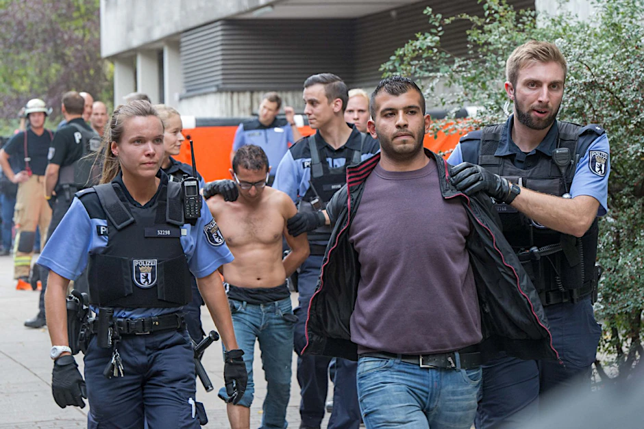 Die Flüchtlinge werden von Polizeibeamten abgeführt.