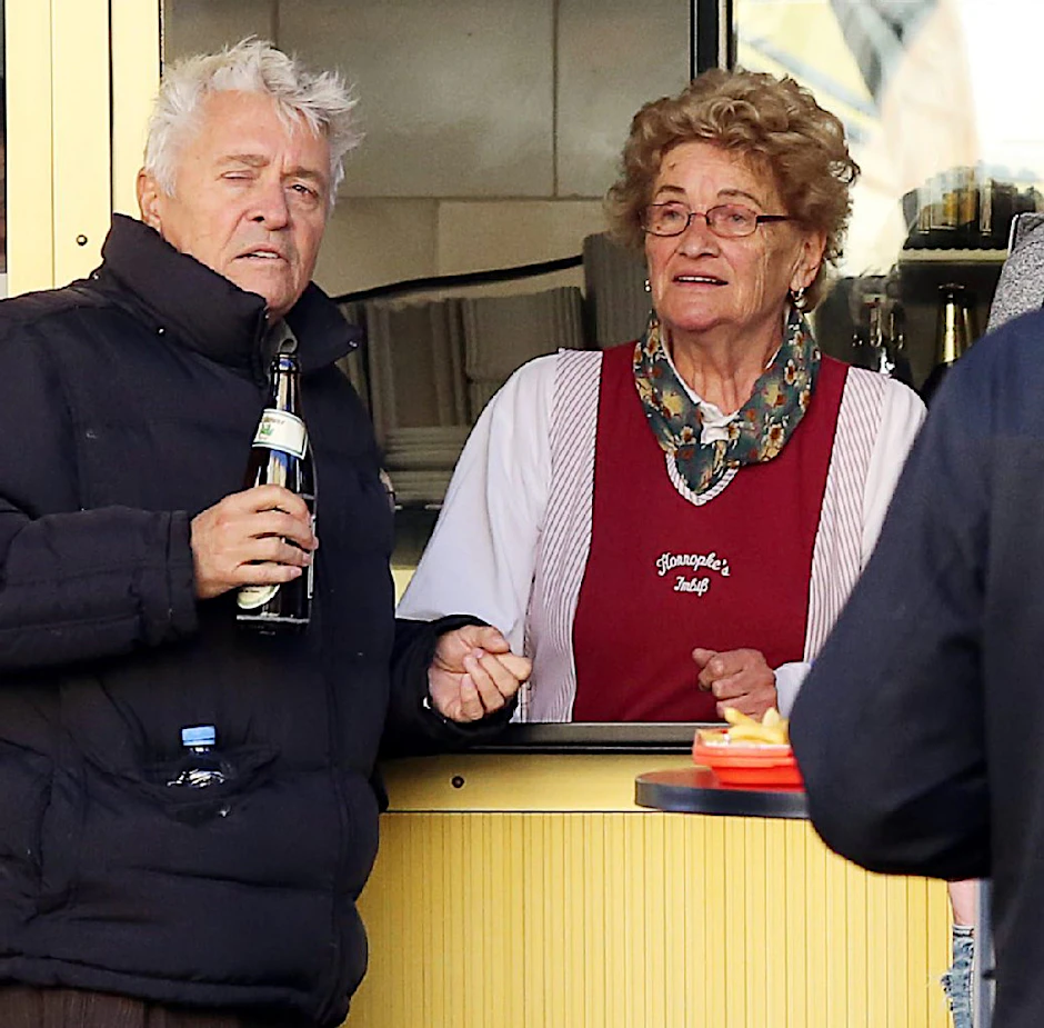 Konnopke-Chefin Waltraud Ziervogel und Henry Hübchen in einer Szene. Sie lächelt, er wirkt mit der Pulle Bier etwas angeschlagen.