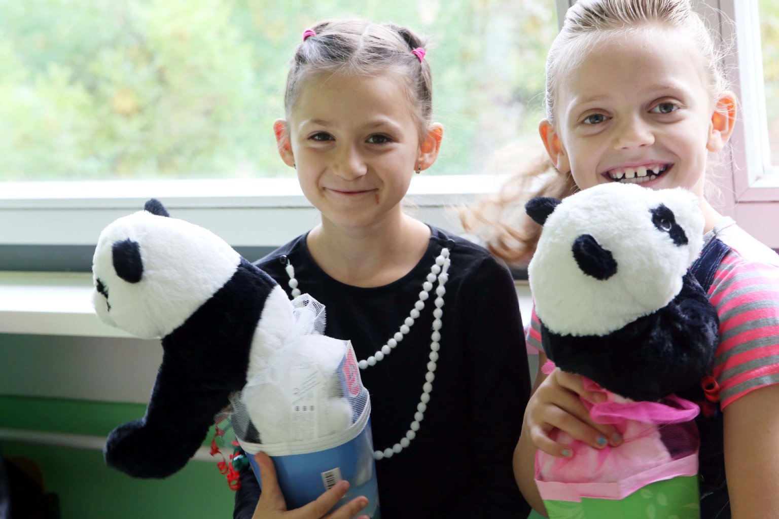 Rijona (8) aus dem Kosovo und Armela (8) halten ihre gespendete Schultüte samt Mini-Panda ganz fest.