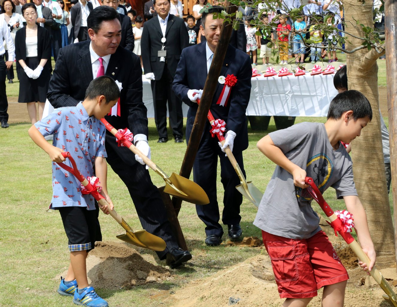 Bürgermeister Yukiui Matsumoto pflanzt mit Kindern neue Bäume.