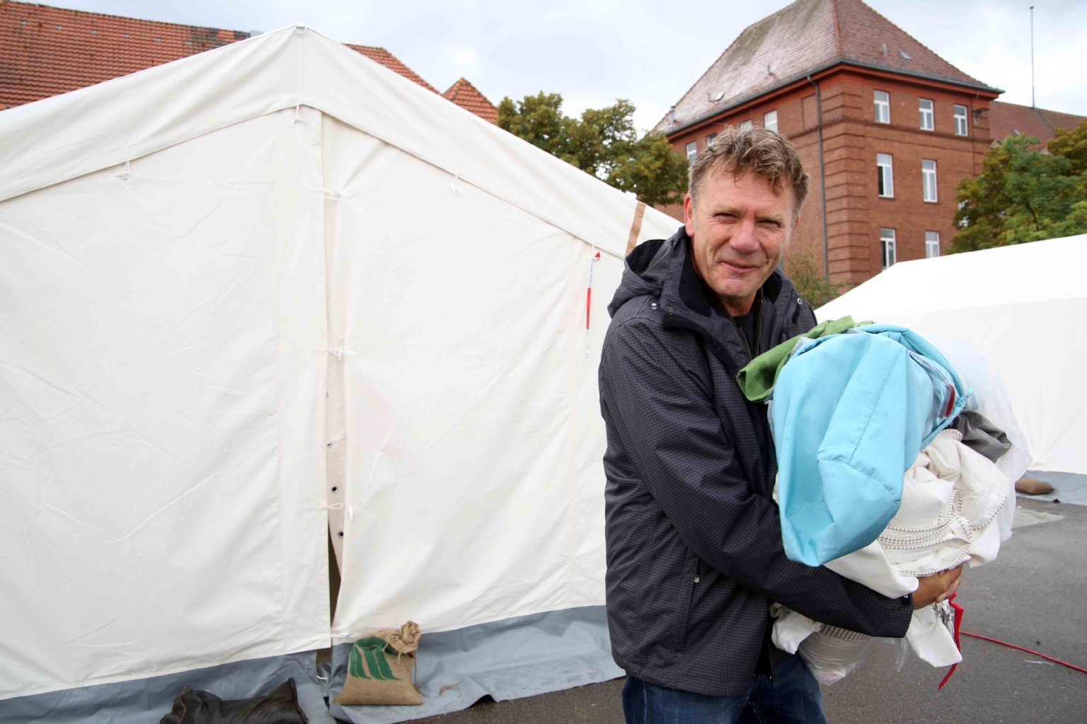 Helfer Thomas aus Spandau bringt Bettzeug für die Zelt-Flüchtlinge auf dem Kasernen-Gelände.