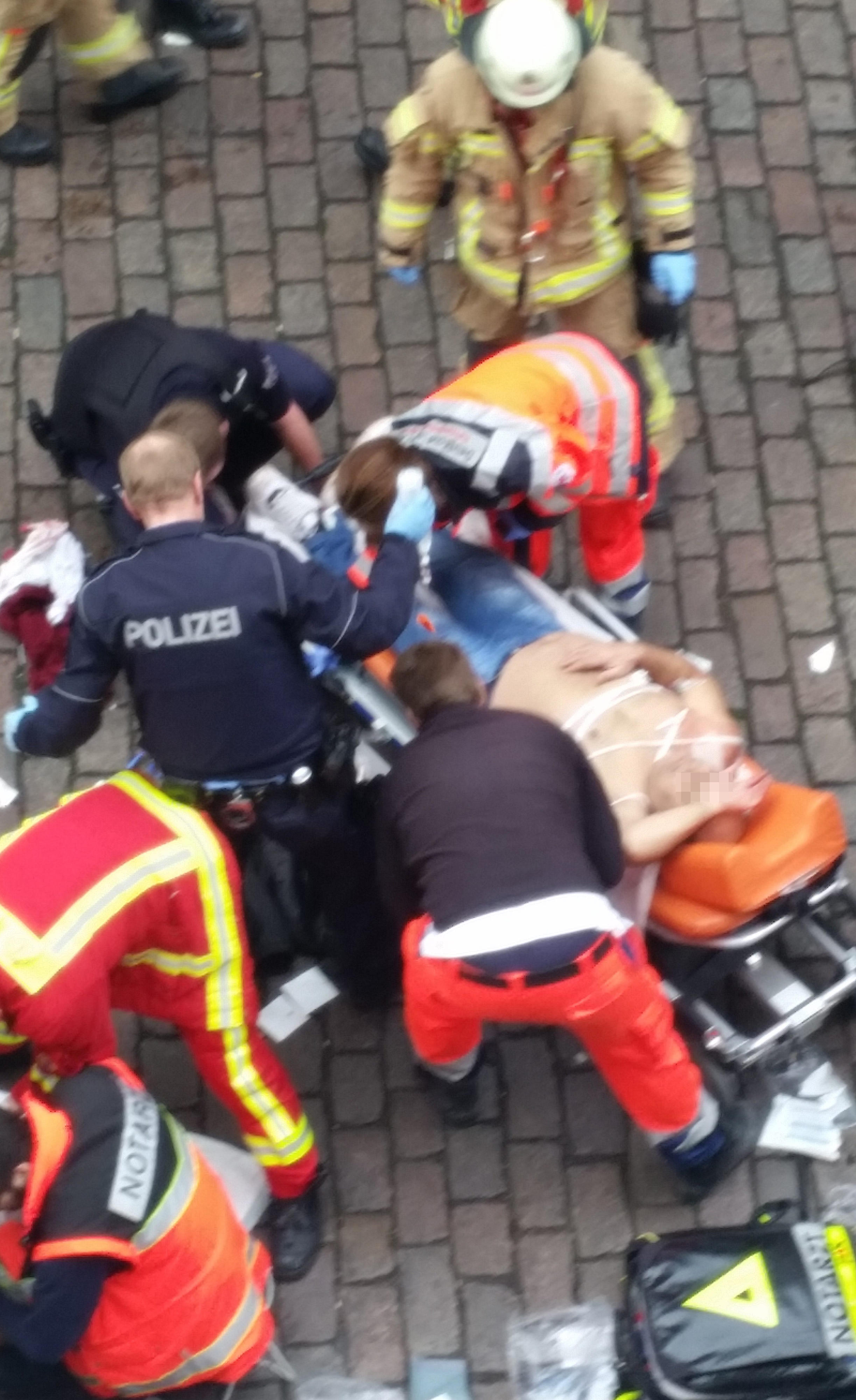 Einer der angegriffenen Männer liegt mit nacktem Oberkörper auf einer Trage der Feuerwehr.  