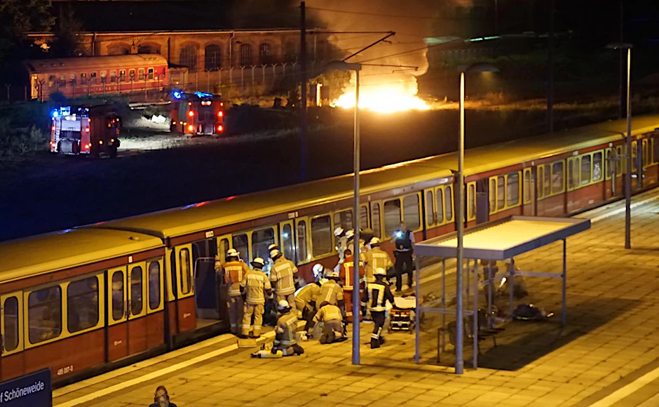 Die Feuerwehr befreite den eingeklemmten Mann. Im Hintergrund löschen andere Einsatzkräfte den Brand auf dem Bahngelände.