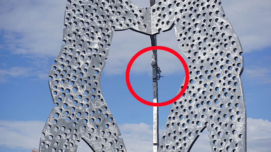 Ein Fahrrad hängt am Molecule Man in Berlin-Treptow.