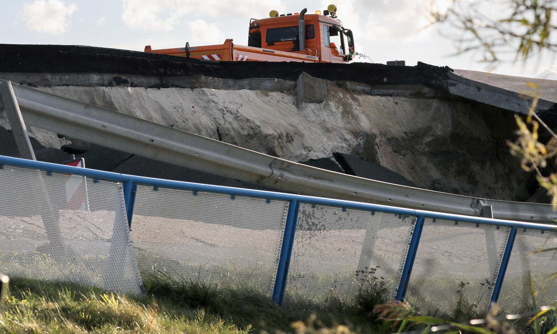 Ein Fahrzeug der Autobahnmeisterei fährt an einem weggebrochenen Stück der Autobahn A20 in Fahrtrichtung Rostock an der Trebeltalbrücke bei Tribsees vorbei.