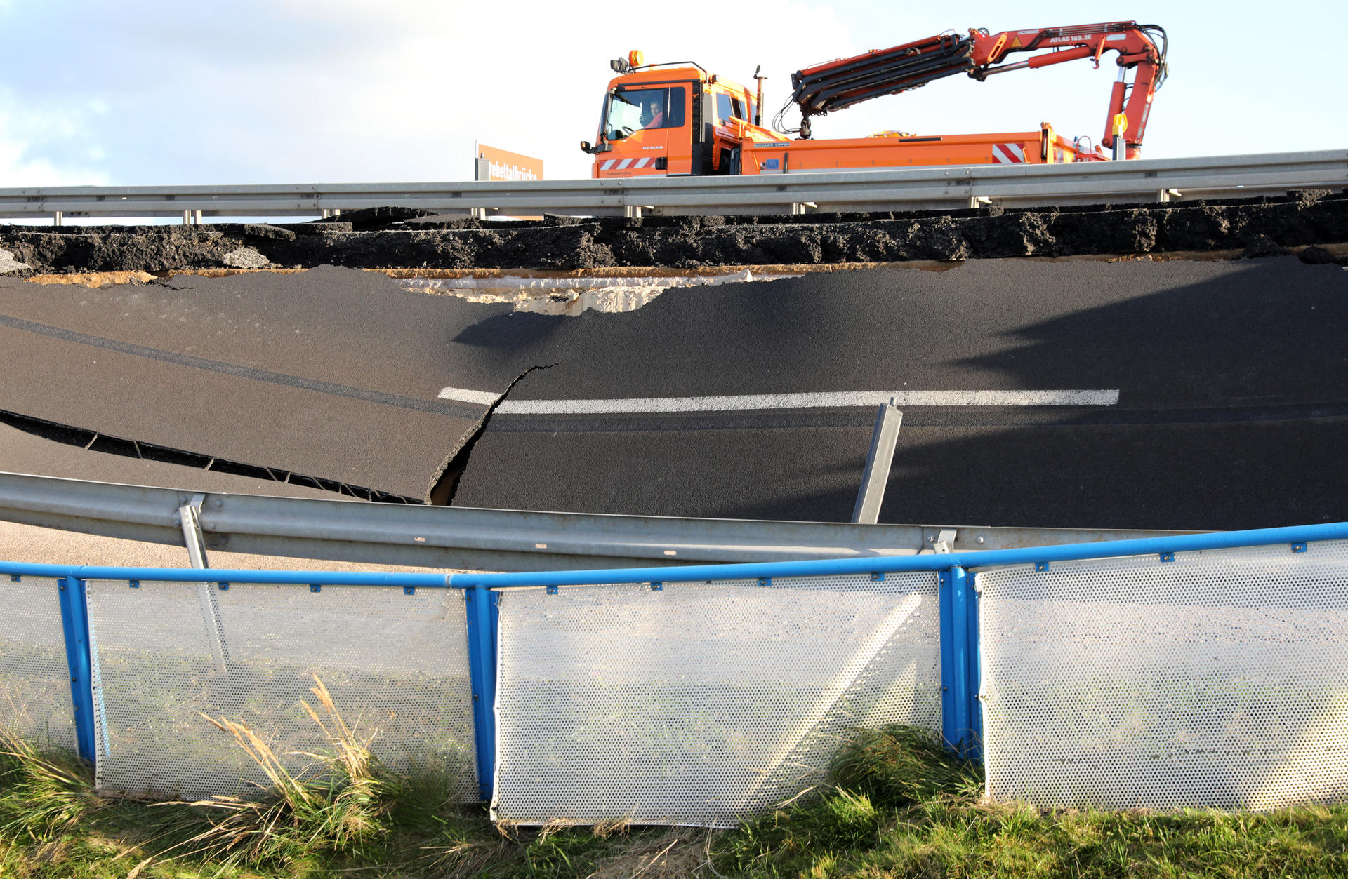 Ein Fahrzeug der Autobahnmeisterei fährt an einem weggebrochenen Stück der Autobahn A20 in Fahrtrichtung Rostock an der Trebeltalbrücke bei Tribsees (Mecklenburg-Vorpommern) vorbei.
