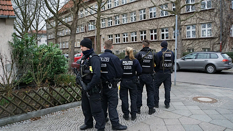 Polizisten sind am Tatort mit Schnellfeuerwaffen im Einsatz.