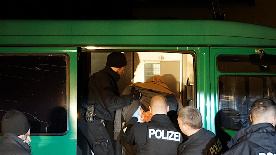 Polizisten transportieren den festgenommenen Mann ab.