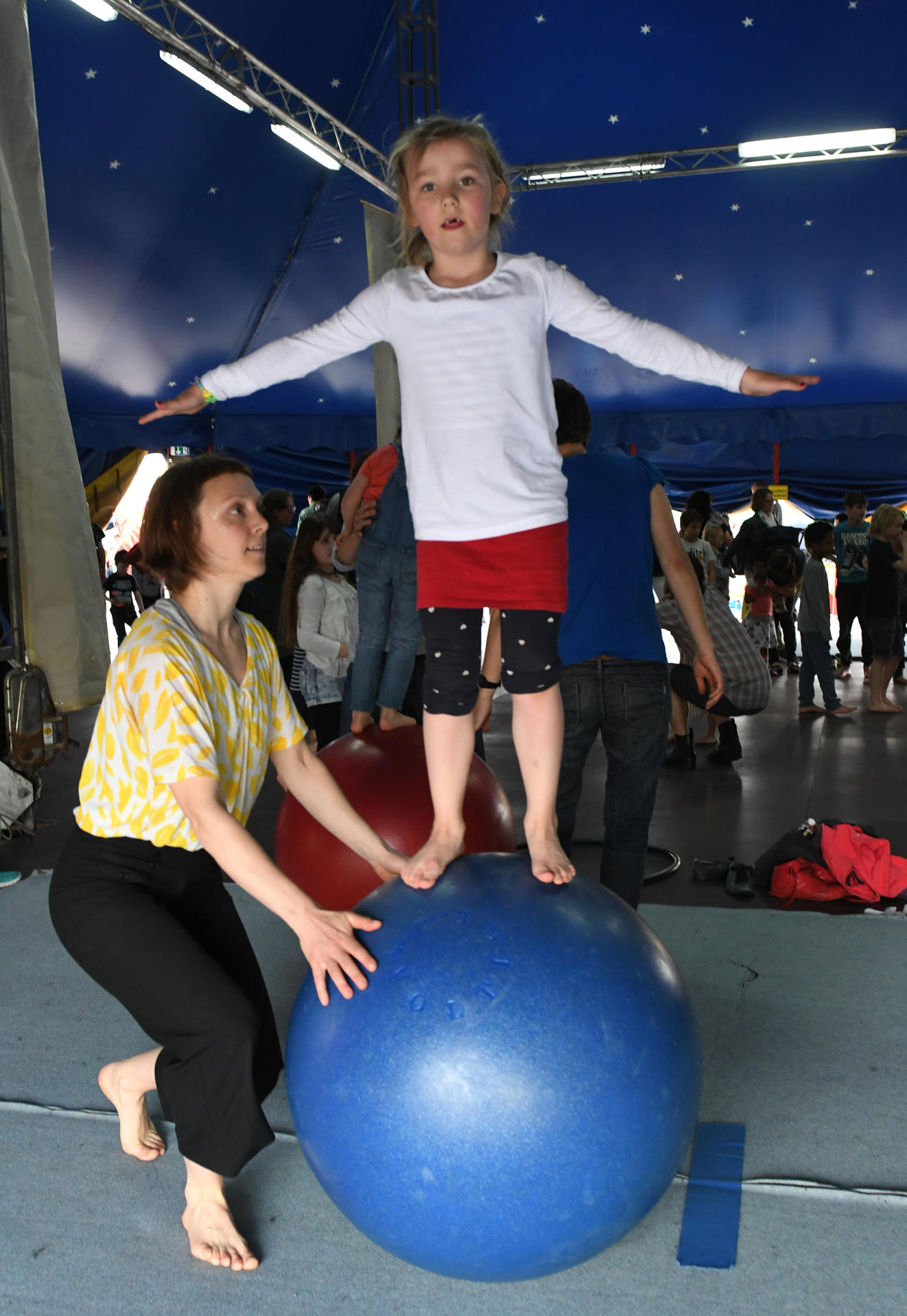 Kia Bunge (6) lernt bei Artisten-Erzieherin Lena Pansegrau (33), wie man auf einem Ball läuft.