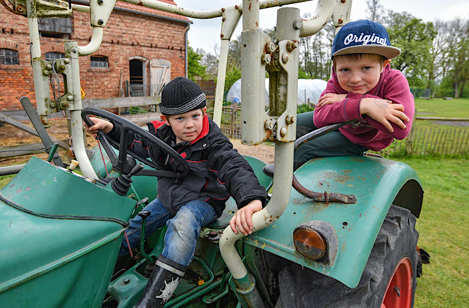Der siebenjährige Jakob Frank (r), und sein Freund Elia, auf einem alten Traktor auf einem Bauernhof in Biesenbrow.