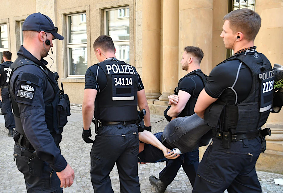 Polizisten führen am 19.05.2017 in Berlin vor dem Bundesjustizministerium einen Demonstranten der "Identitären Bewegung" ab. Auch der gesuchte soll an dem Protest teilgenommen haben.