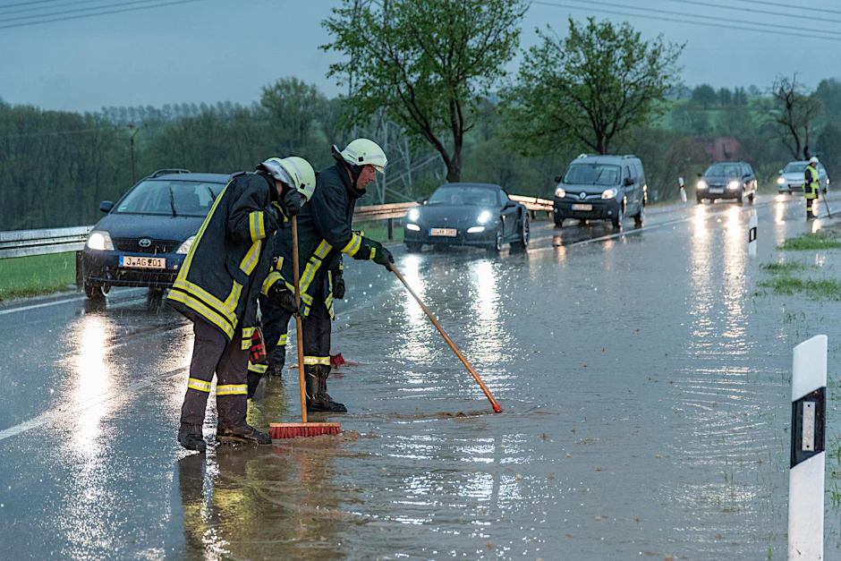 Feuerwehrleute kämpfen nach heftigem Regen gegen die  Wassermassen auf der  Bundesstraße B7 zwischen Weimar und Jena.