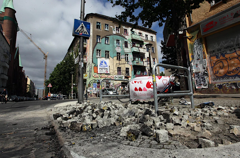 Der Tag nach dem Exzess: Ein Haufen loser Pflastersteine liegt vor einem Plakat, auf dem ausgerechnet „Love“ geschrieben steht. 