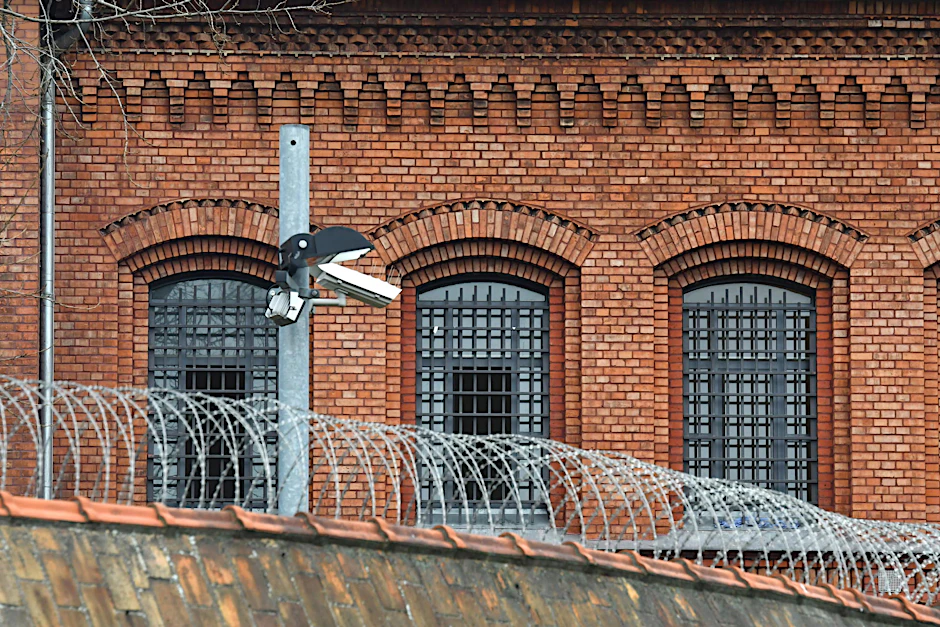 Vergitterte Fenster der Justizvollzugsanstalt (JVA) Plötzensee in Berlin mit einem Strahler und einer Videokamera davor.