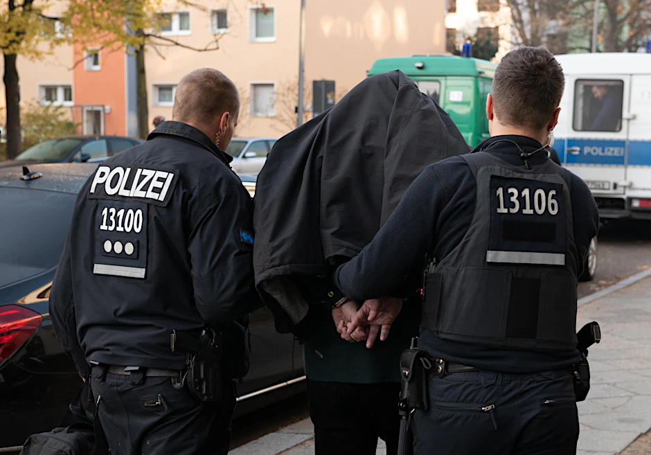In Handschellen bringen Polizisten ein Clan-Mitglied auf die Wache.