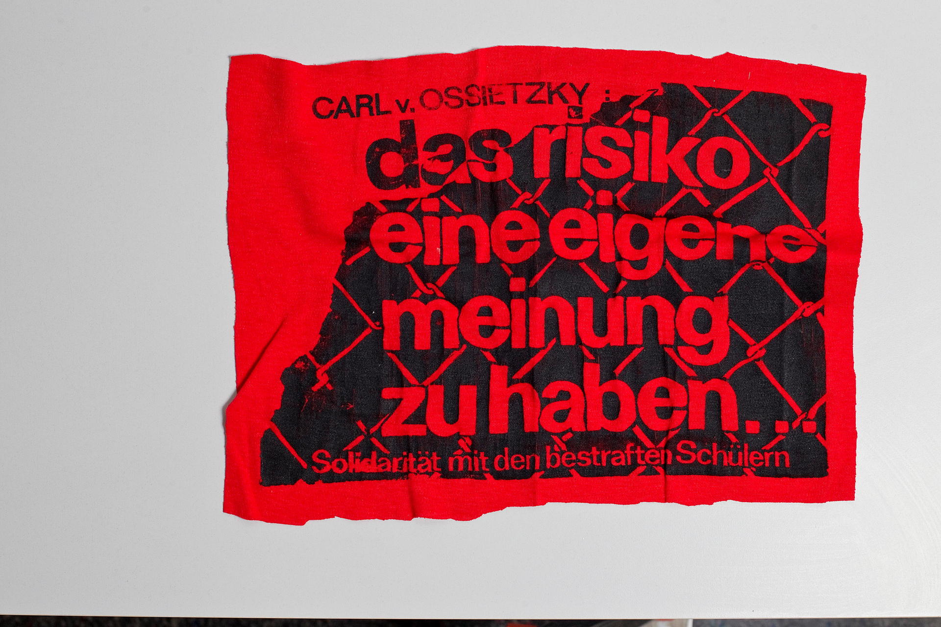 Ein Stück Stoff mit einem Zitat des Nazi-Opfers Carl von Ossietzky: Mit so bedruckten T-Shirts konnten Mutige Solidarität mit den Schülern der Pankower Ossietzky-Schule zeigen. Die meisten trugen es aber unter dem Hemd. Acht Schüler waren 1988 Ziel von Repressionen, weil sie offen gegen DDR-Paraden, Rechtsextremismus in der DDR und für die polnische Solidarnosc eintraten. Vier Schüler wurden von der Schule entfernt, konnten erst nach der Wende 1989 das Abitur nachholen.