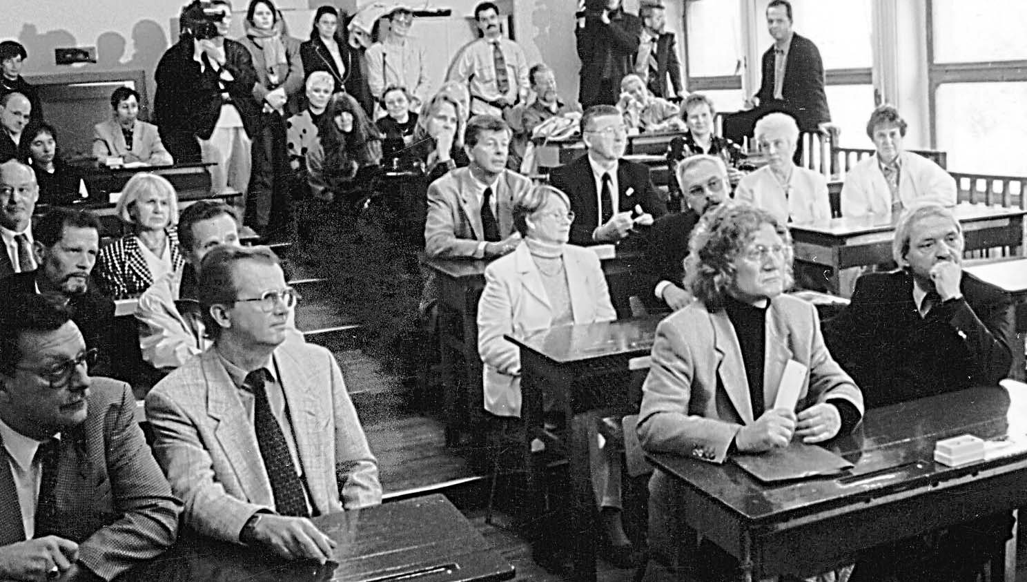 Klassentreffen: Die ehemaligen Schüler und Schülerinnen kommen 1996 in ihrer alten Schule in Storkow zusammen; sie nehmen ihre alten Plätze im „Stufenraum“ ein, wo sie 1956 ihre ersten Schweigeminuten einlegten. Dietrich Garstka sitzt vorne rechts.