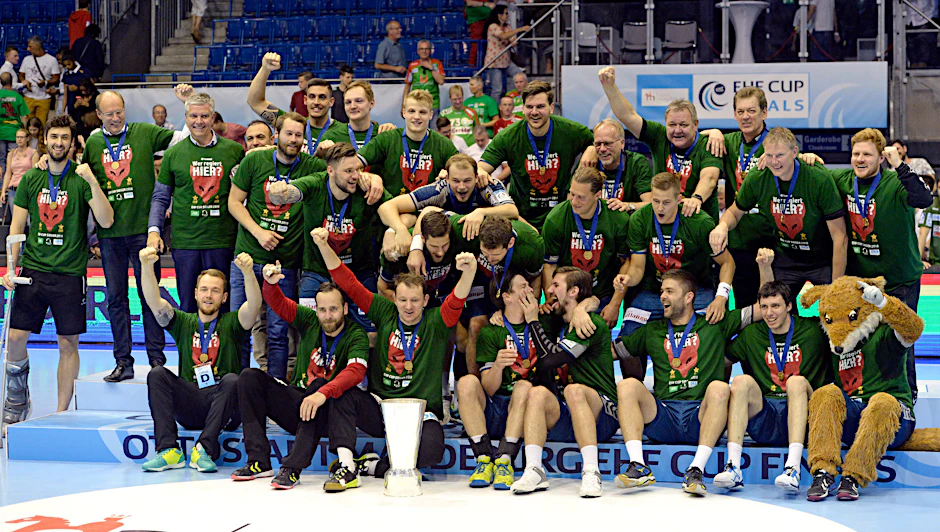 Glückliche Füchse in Siegershirts und mit EHF-Pokal.