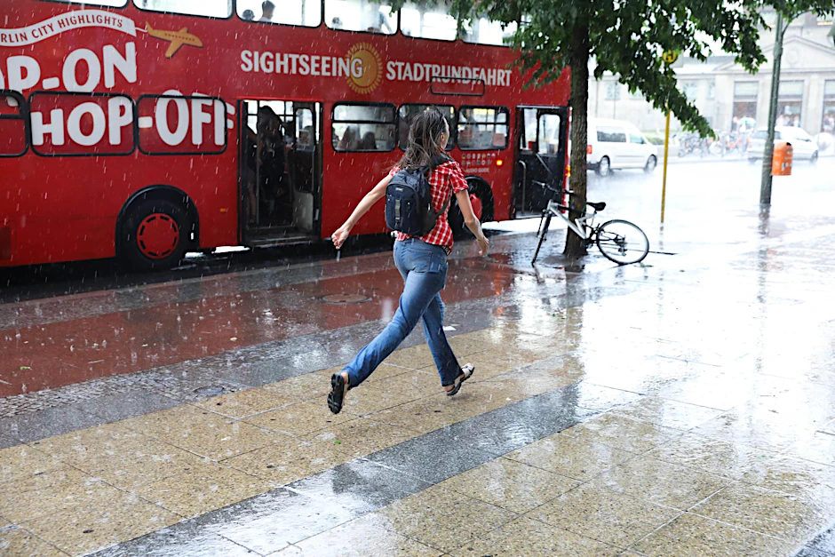 Passantin flüchtet vor Starkregen in der Tauentzienstraße. 