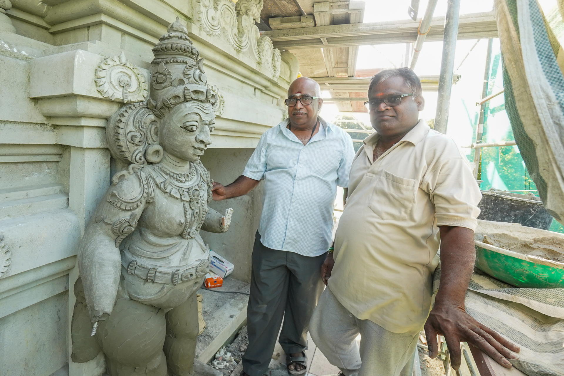 Vorstandsmitglied Krishnamurthy (l) und Architekt Ravishankar stehen vor dem Eingangstor des demnächst entstehenden Hindu-Tempels. 