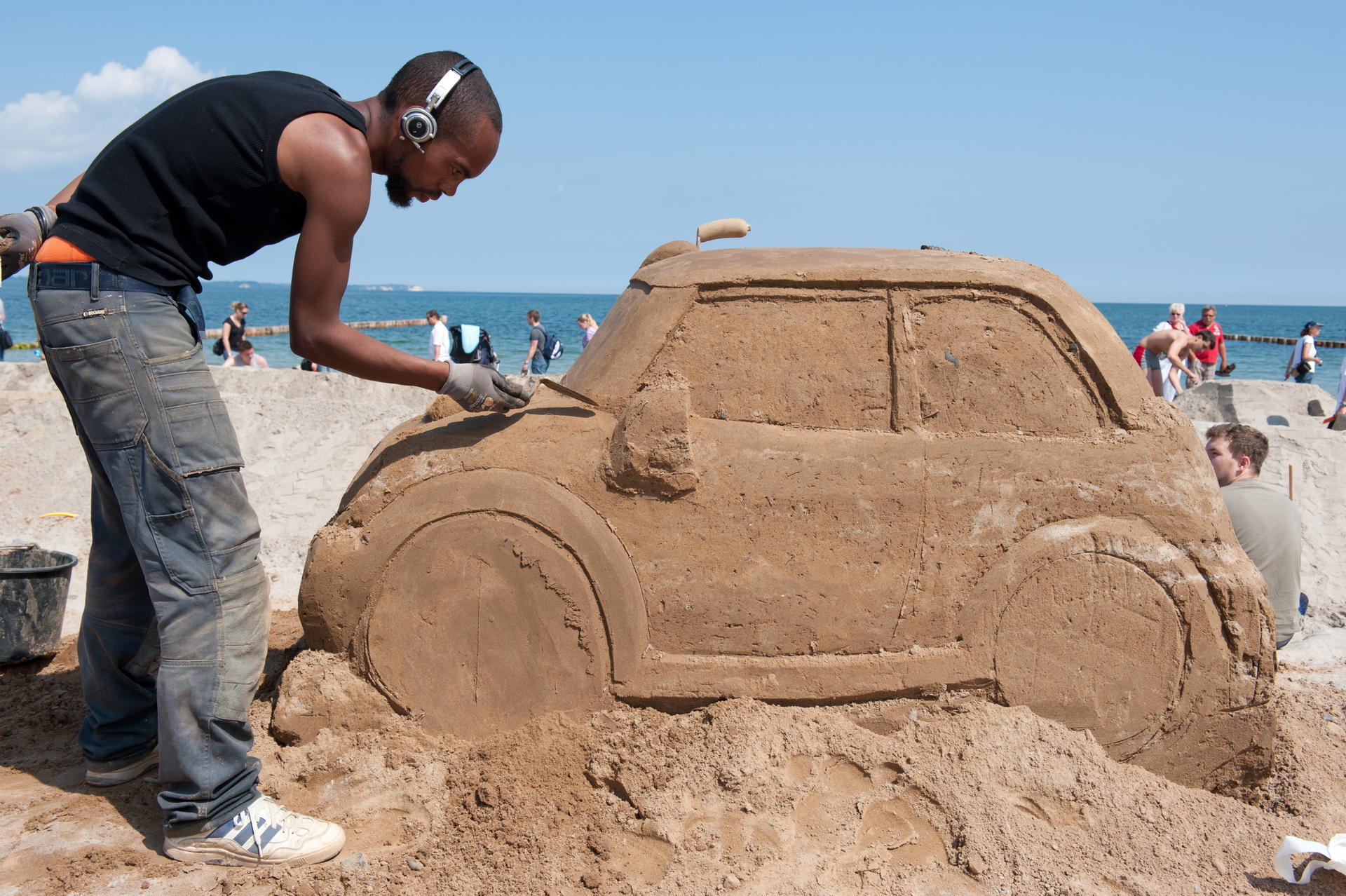 Der Bildhauer Bouke Atema aus den Niederlanden baut am Strand des Seebades Glowe auf der Ostsee-Insel Rügen an einem Auto aus Sand.