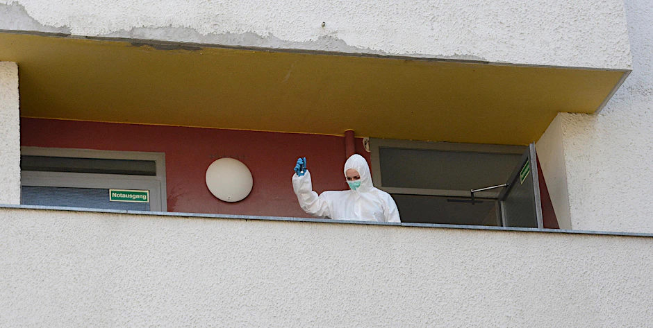 Eine Polizistin leuchtet mit einer Taschenlampe den Balkon der Todes-Wohnung aus. 