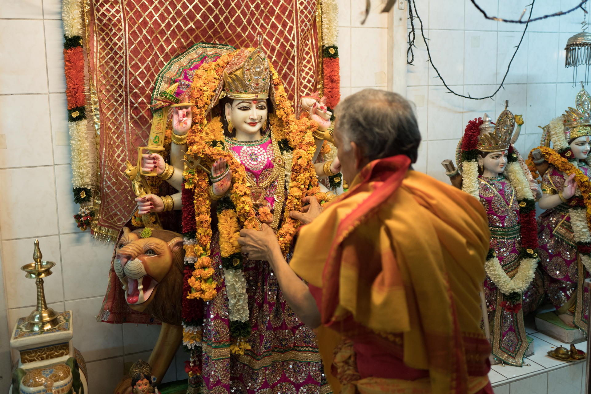 Die Figur einer Hindu-Göttin wird von einem Mitglied der Hindu-Gemeinde geschmückt.