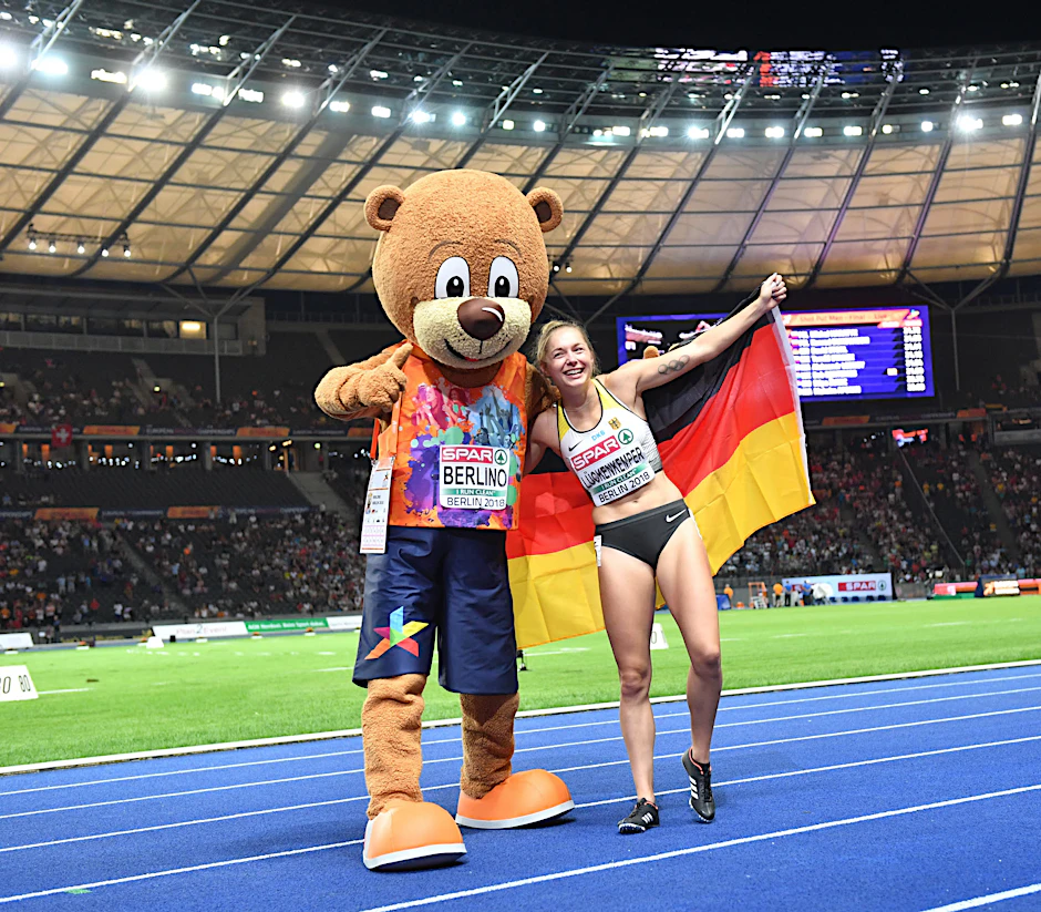 Gina Lückenkemper (Bahn 6) beim Zieleinlauf und dann mit EM-Berlino Maskottchen.