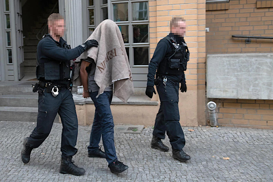 Polizisten führen einen verdächtigen Mann nach der Razzia gegen kriminelle Mitglieder arabischer Großfamilien in der Pohlstraße ab.