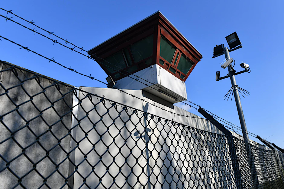 Sicherheitsleuchten und Überwachungskameras vor einem Gebäude auf dem Gelände der Justizvollzugsanstalt Tegel.