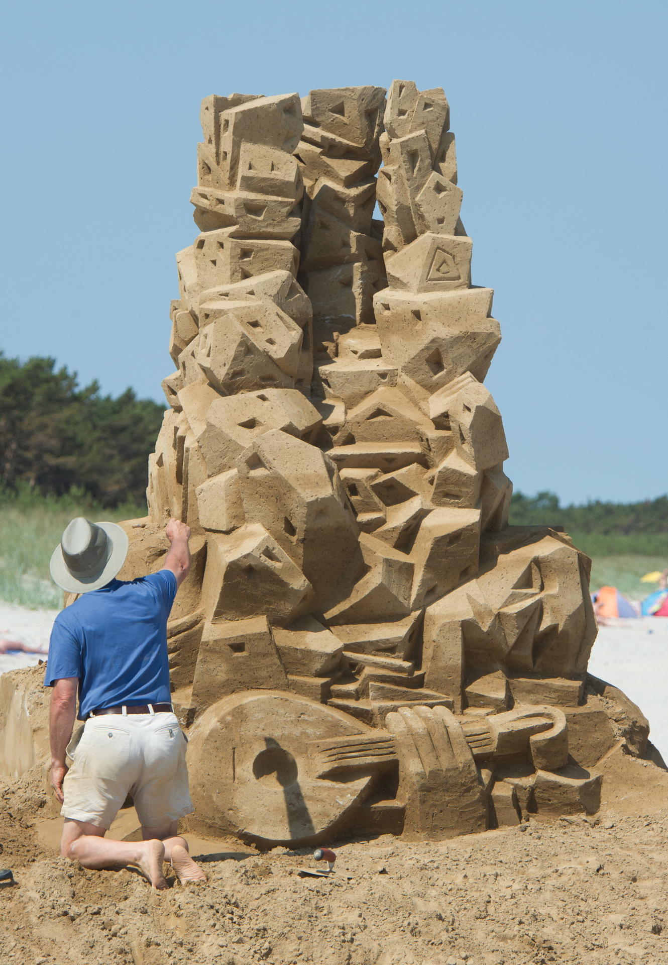 Ein Bildhauer arbeitet an seiner Skulptur am FKK-Strand des Seebades Glowe.