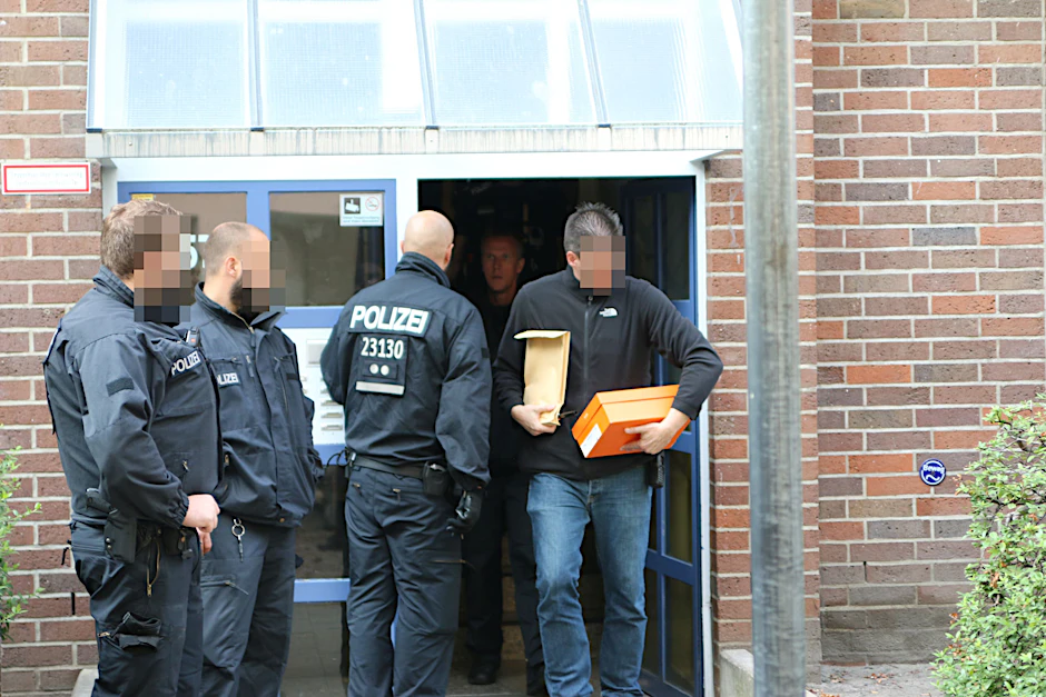 Kriminalbeamte stellen Beweismittel sicher. Neben einer Schreckschusspistole wurden auch Telefone beschlagnahmt.