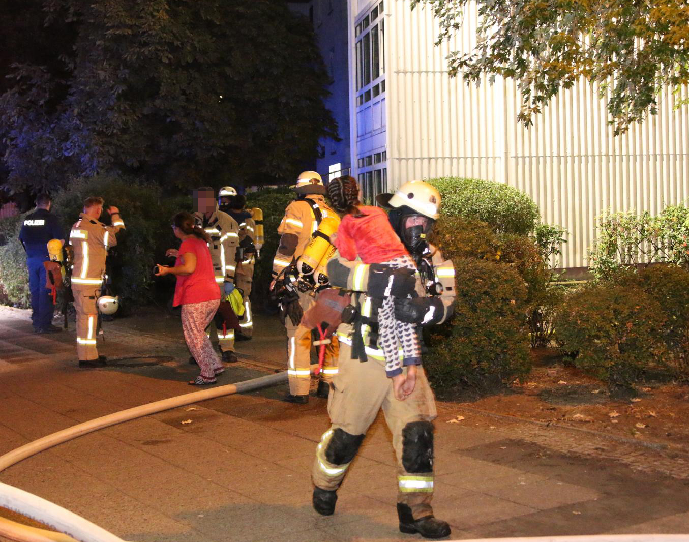 Feuerwehrmann bringt ein Kind vom Brandort in Sicherheit.