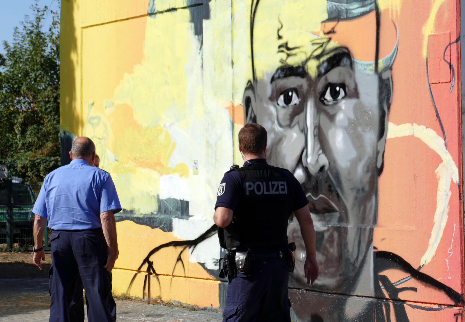 Ein Polizist schaut auf das Graffiti an der Oderstraße. Eine Malerfirma soll es unter Polzeiaufsicht überstreichen.  