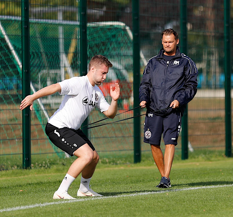 Vincent Rabiega arbeitet konzentriert  mit Physio Adrian Marklowski und dem Gummiband.