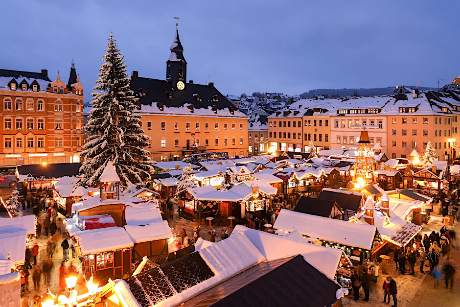 Schneebedeckte Hütten auf dem Weihnachtsmarkt im sächsischen Annaberg-Buchholz: Von so einem Winterwunderland können wir zu Weihnachten hierzulande leider nur träumen.