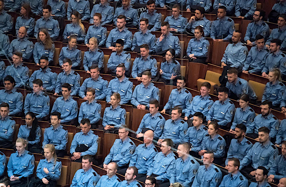 Junge Polizeibeamte sitzen bei der feierlichen Vereidigung der Berufsanfänger des mittleren und gehobenen Dienstes bei der Berliner Polizei.