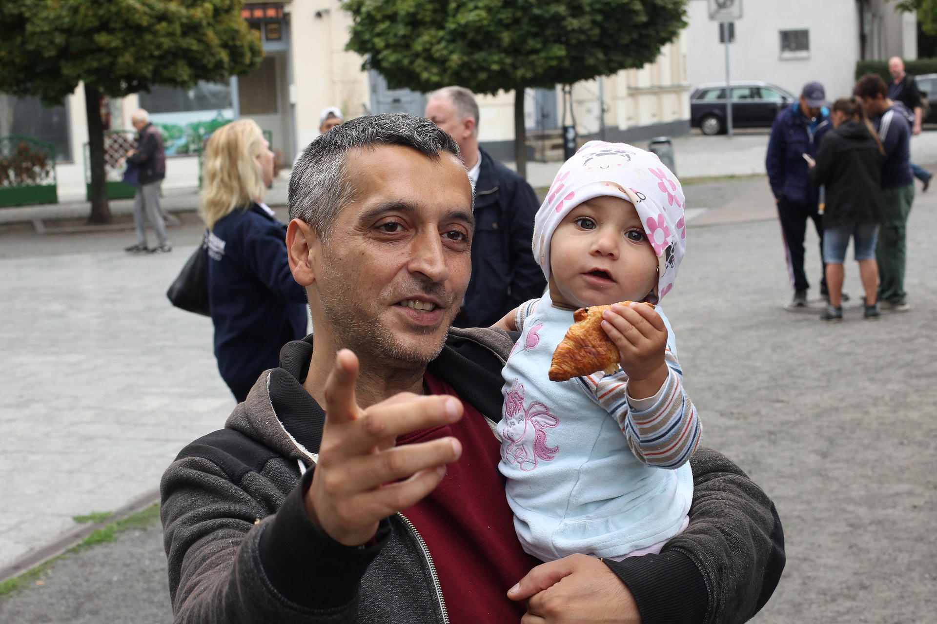 Monti (41), einer der Unterstützer vom Franz-Neumann-Platz, hält das Kind eines Bedürftigen auf dem Arm, das sich über ein Buttercroissant freut. 