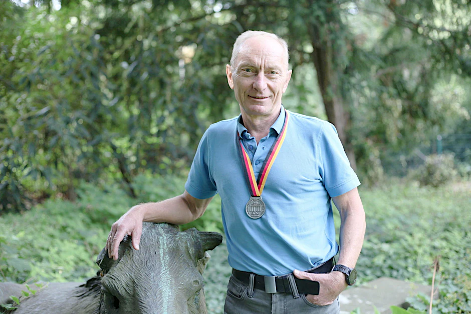 Jürgen Götte im Garten hinter seinem Bürohaus im Tiergarten. Um den Hals trägt er einer seiner zahlreichen gesammelten Marathon-Medaillen.