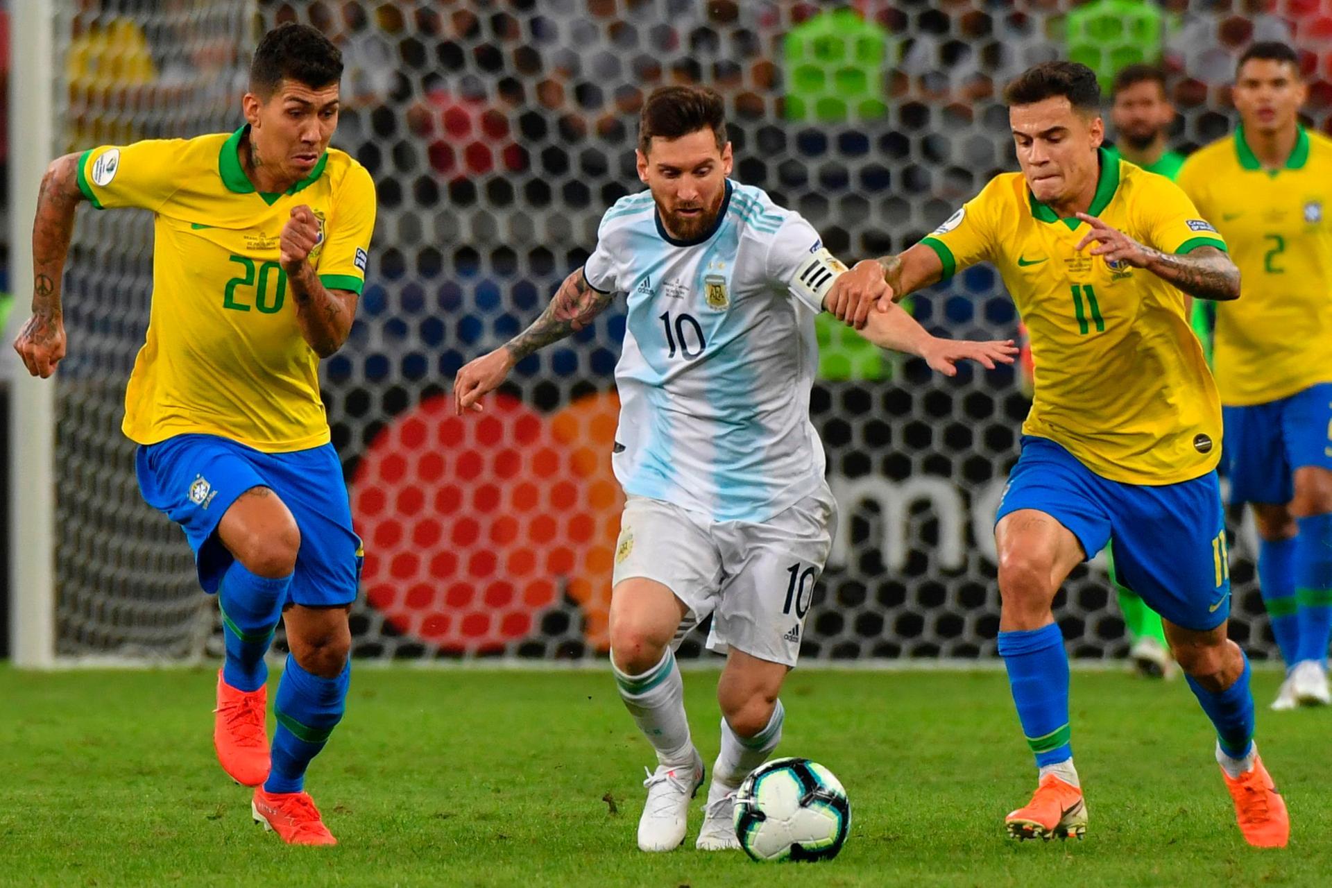  Lionel Messi (M.) wird von den Brasilianern Roberto Firmino (l.) and Philippe Coutinho in die Zange genommen. 