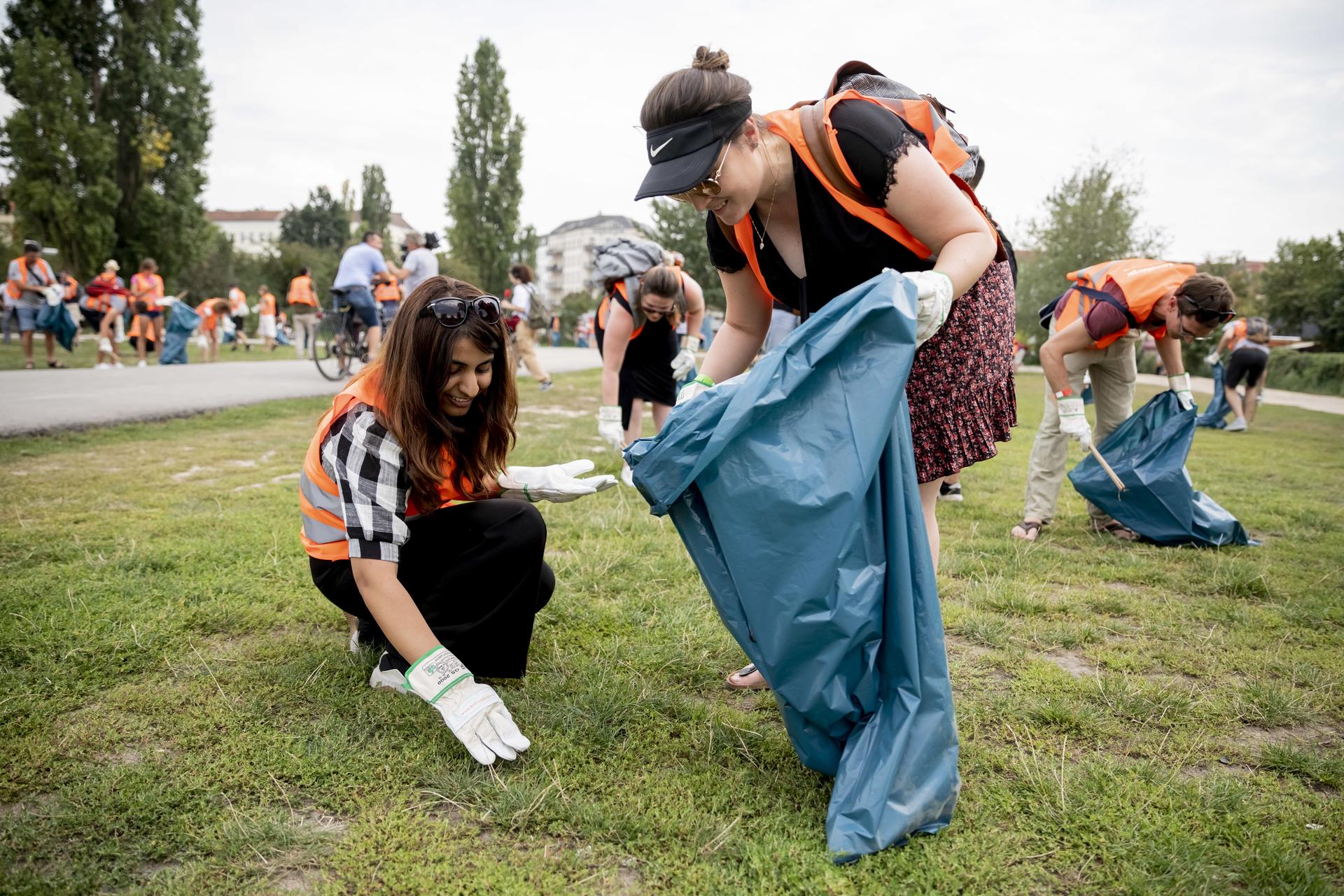 Hiral Arora (l), Studentin aus Indien, und Camila Wolfram, aus Brasilien stammende Studentin in Berlin, sammeln bei einer Stadttour mit Müllsammeln im Mauerpark Müll.