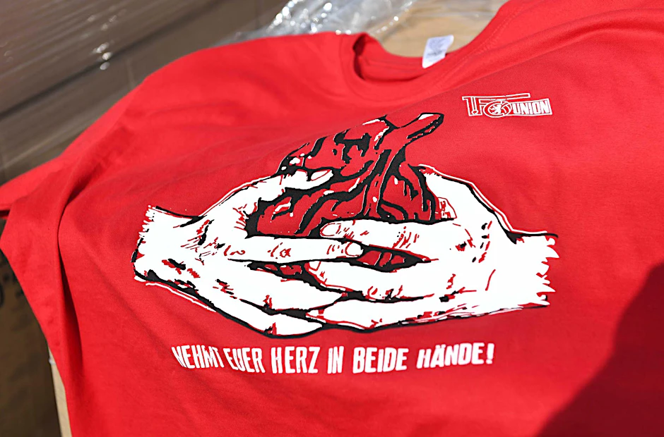 „Nehmt euer Herz in beide Hände!“ Diese T-Shirts wird Union heute kostenlos vor dem Stadion verteilen.