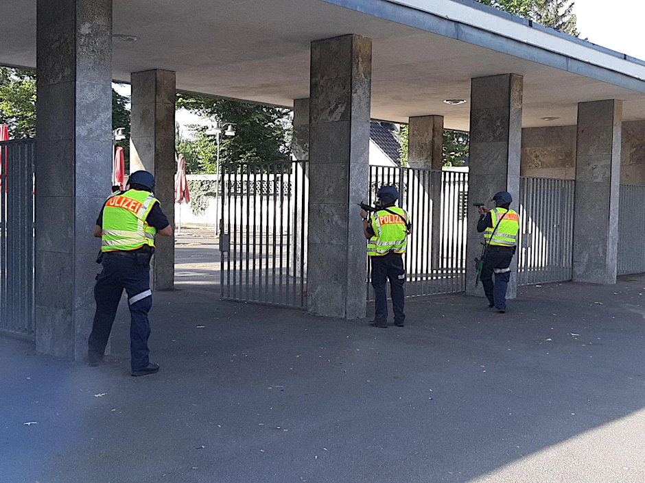 Polizisten mit Maschinenpistolen sichern einen der Eingänge zum Stadion. 