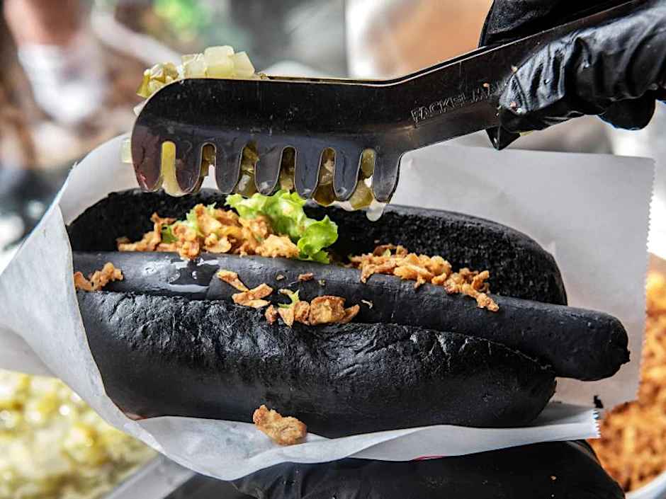 Ein Mann bereitet beim „Black Food Festival” einen Hot-Dog vor. 