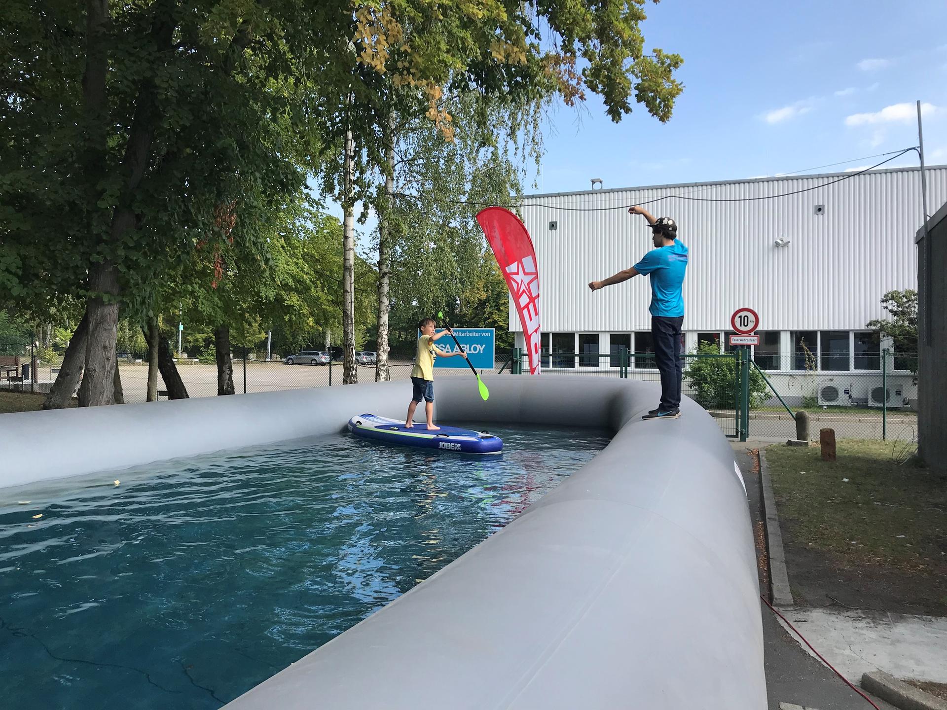 Simon (8) probiert beim Hoffest des Goerzwerks das Stehpaddeln aus. Der Hilfe des Coaches Leonhard (22) bedurfte er gar nicht, kam trocken aus dem Becken raus. Philipp Wilhelm (24) verkauft die niederländischen Bretter - teilweise sind sie aufblasbar - im Goerzwerk, verleiht sie auf dem Schlachtensee.