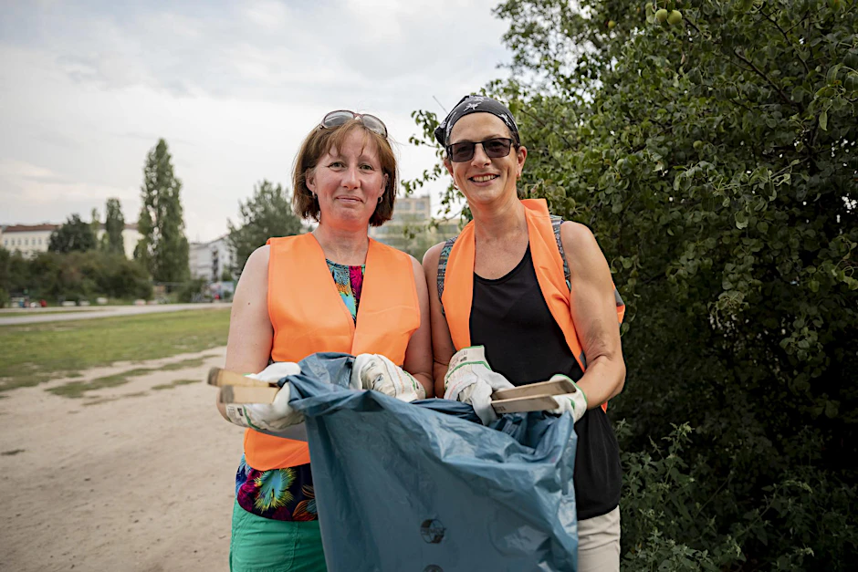 Nicky Jenkins (l) und Jo Tuna, beide Touristinnen aus England, stehen bei einer Stadttour mit Müllsammeln im Mauerpark Müll.